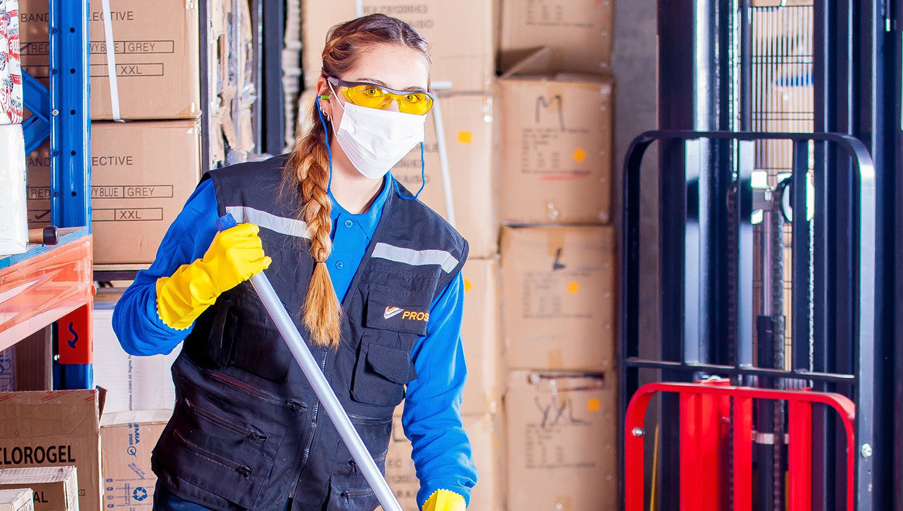 Woman cleaning Commercial cleaner washing an office floor while wearing health and safety equipment