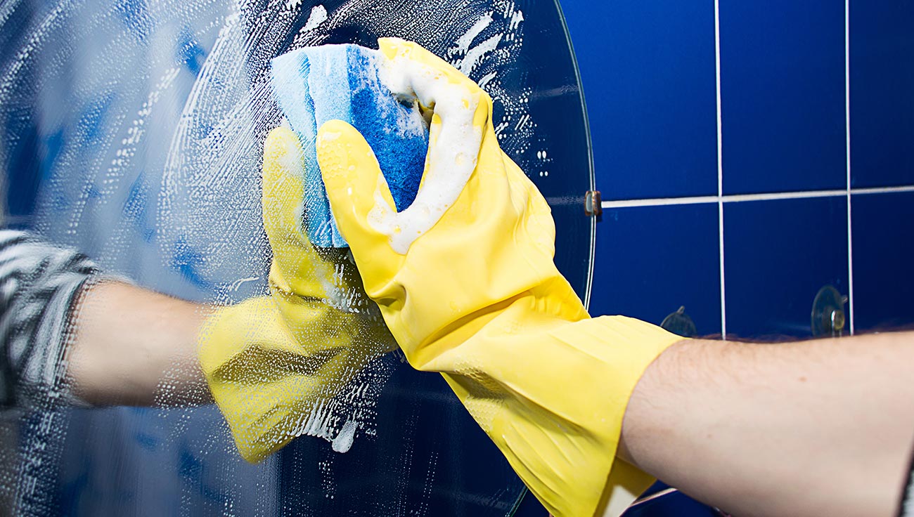 Wall cleaning Professional cleaner wiping a mirror using eco-friendly products in Hertfordshire